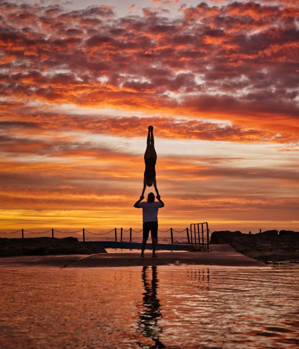 Silhouette of a man in a balancing yoga pose at sunset.